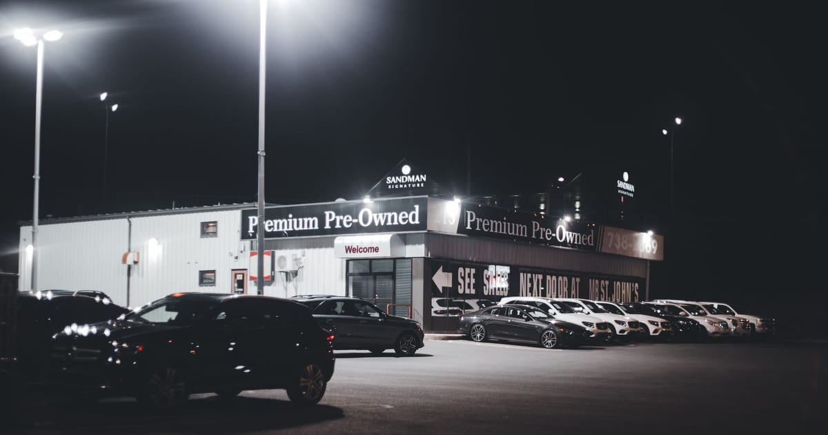A used-car forecourt lit up at night.