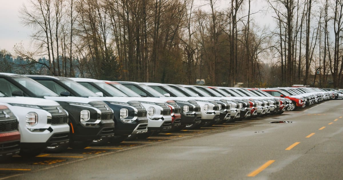 A long row of new cars parked nose-out at a dealership.